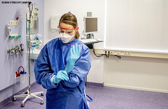 A healthcare worker puts on PPE